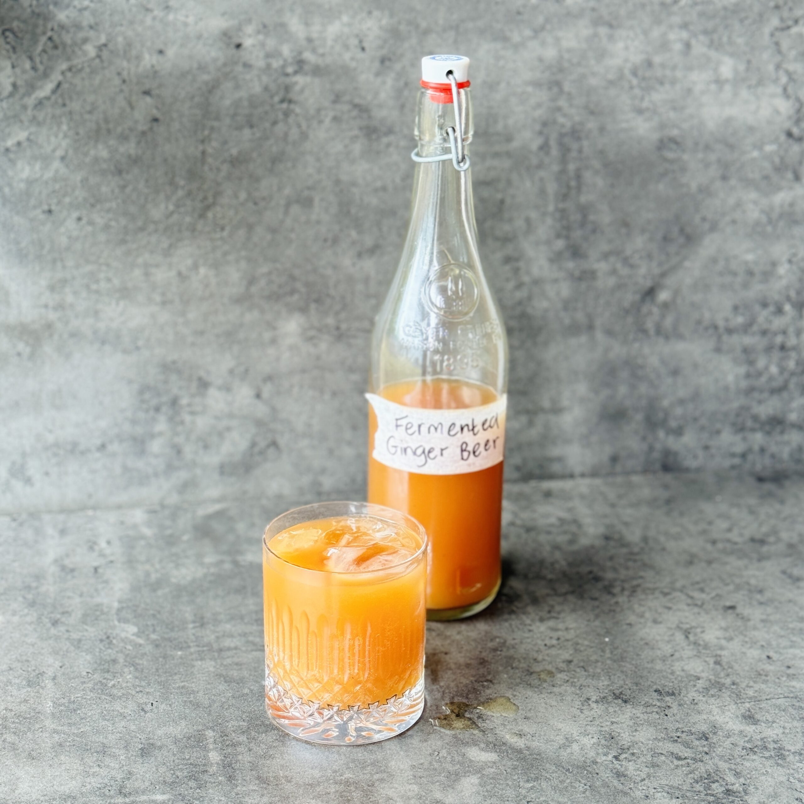 photo of a bottle of homemade fermented ginger beer and a full glass next to it