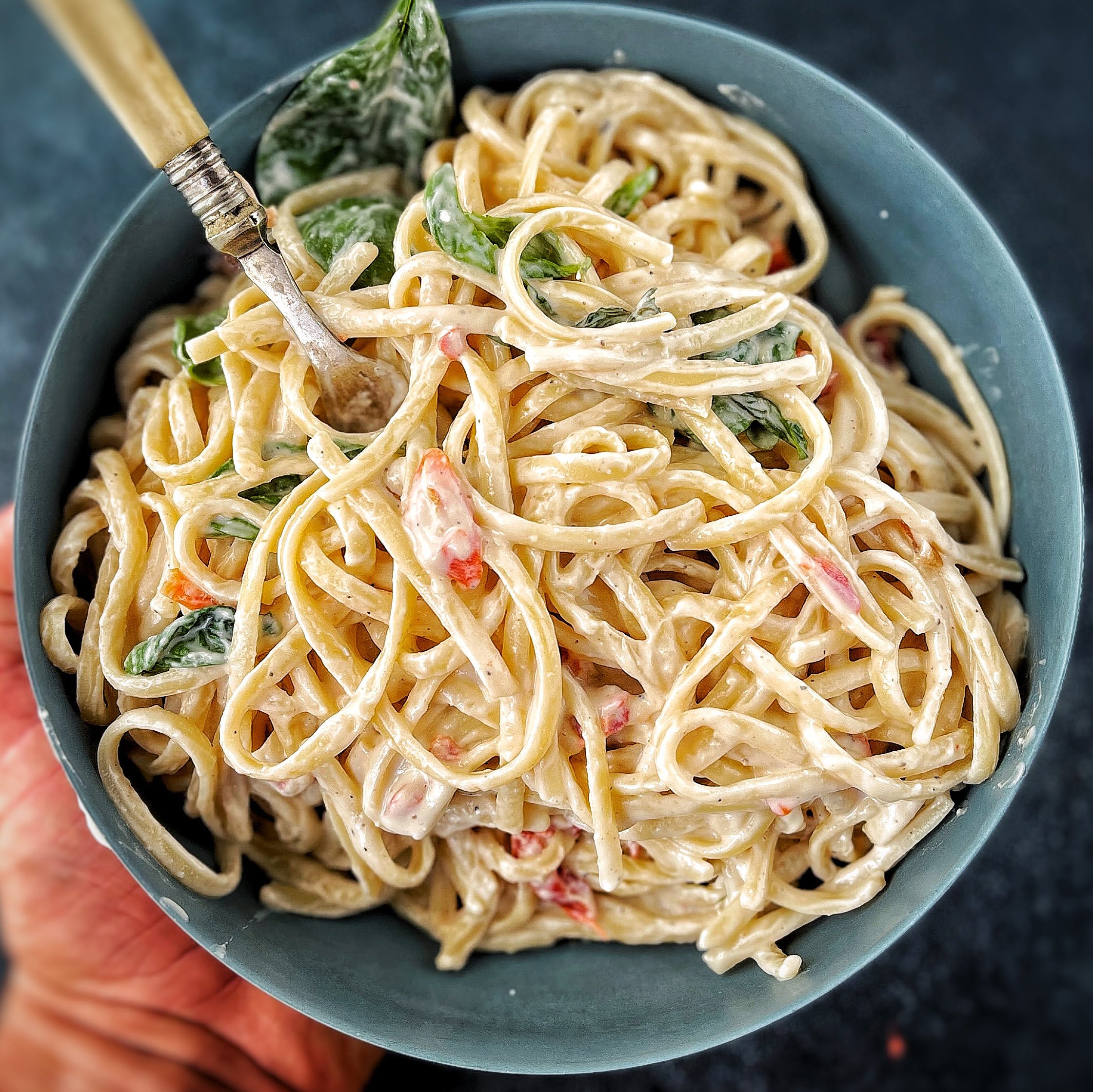 An image of Pasta Alfredo with tomato and basil