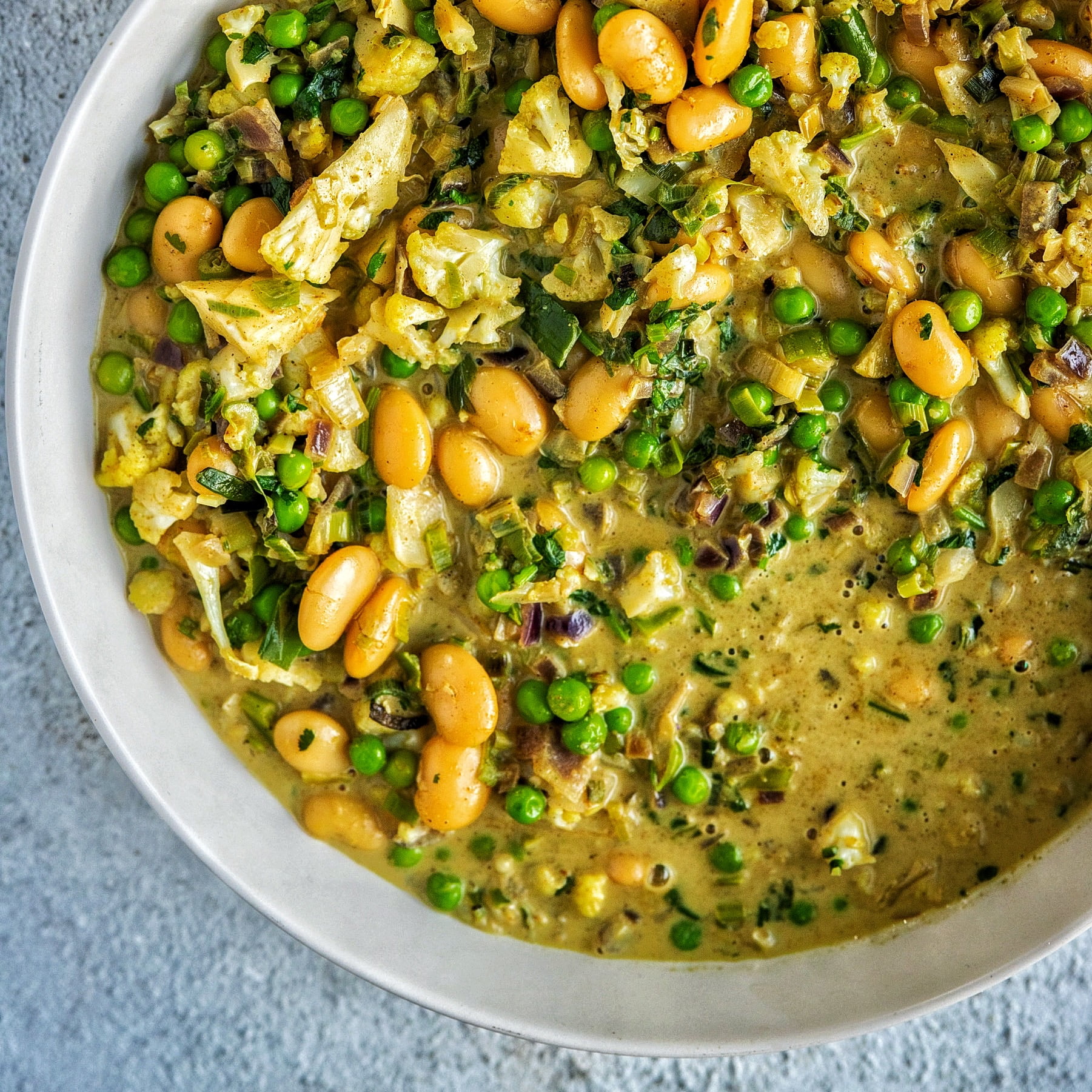 An image of tinned coconut milk and veg and some cooked beans