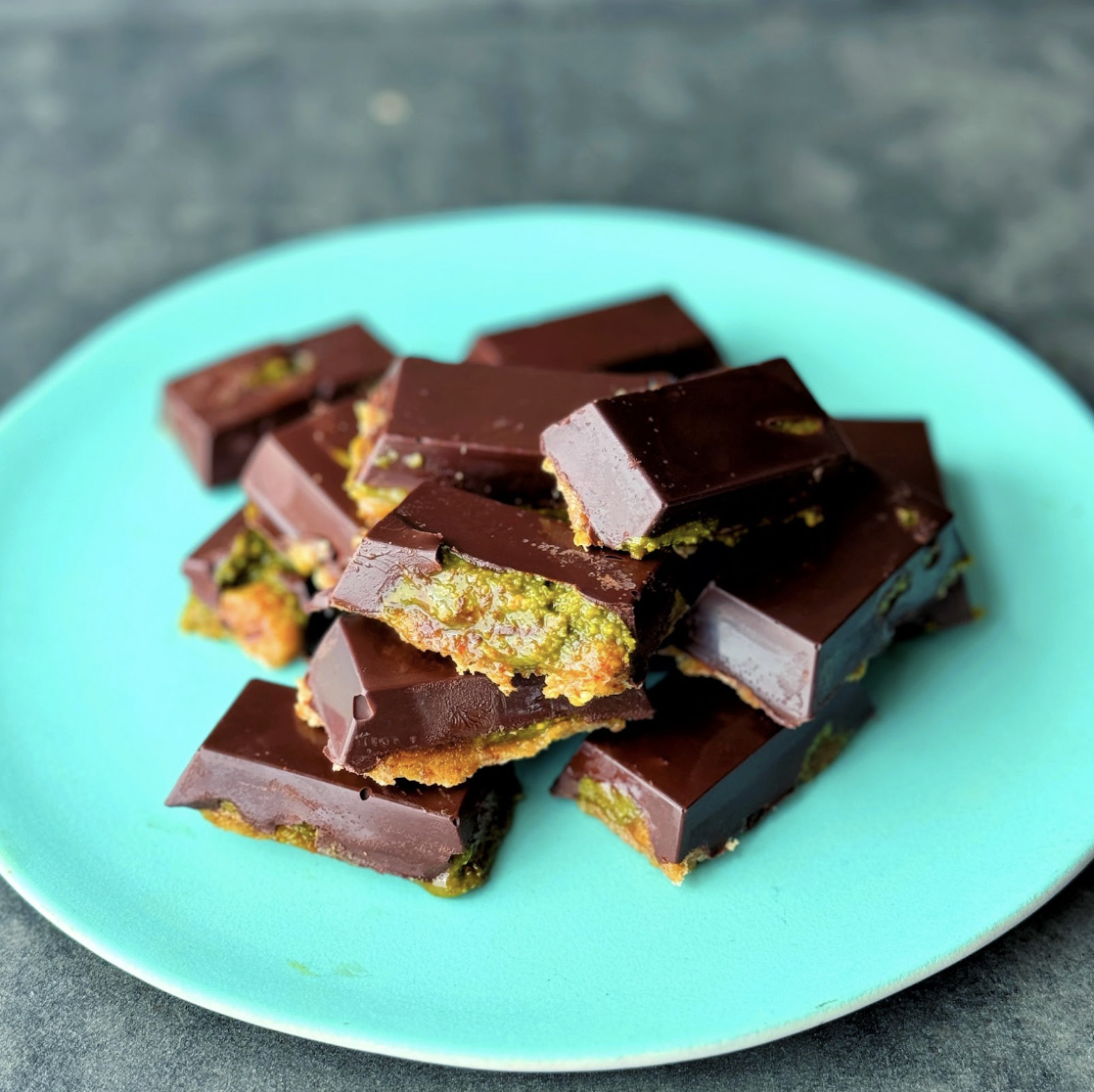 a photo of a turquoise plate containing Triple Layer Chocolate Pistachio Bites